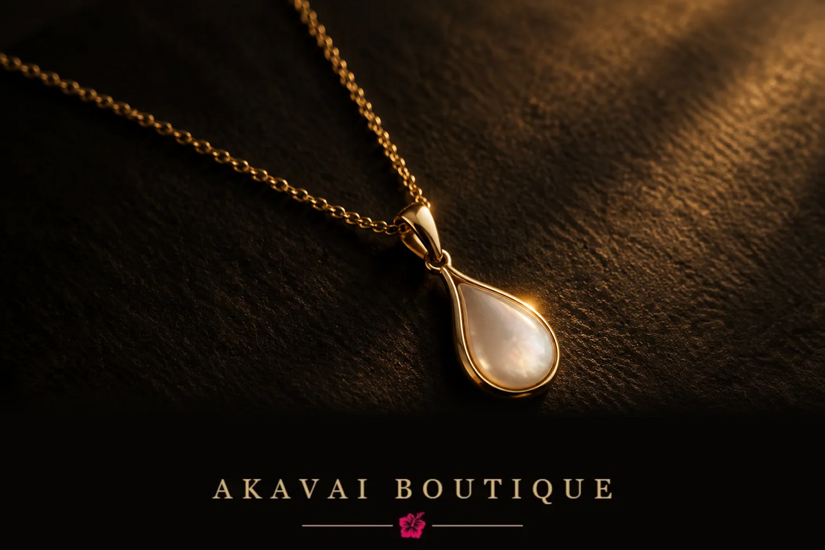Bijou doré Akavai Boutique posé sur fond noir, lumière dorée tamisée, jour de l'ouverture.