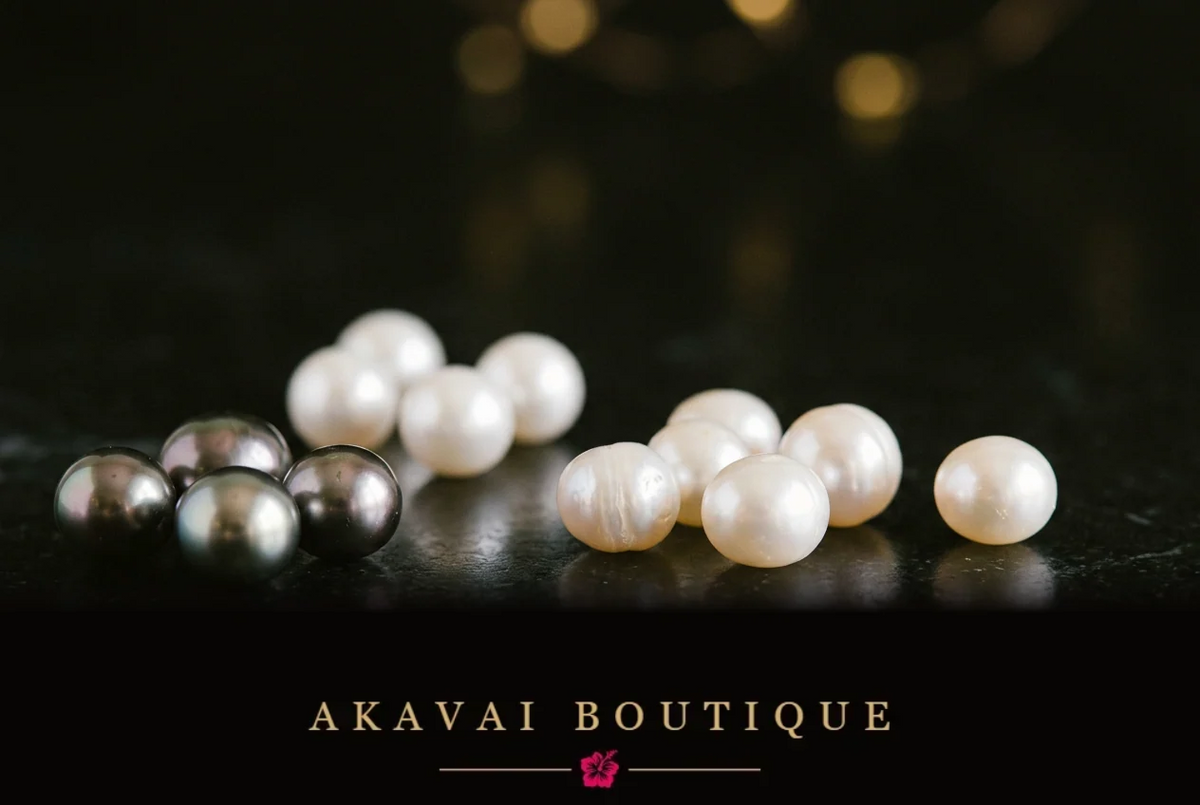 Perles aux nuances anthracite et ivoire sur une surface sombre, lumière chaude et reflets dorés, illustration du Journal d’Akavai sur les différents types de perles