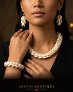 Parure de coquillages blancs portée avec collier, bracelet et boucles d’oreilles